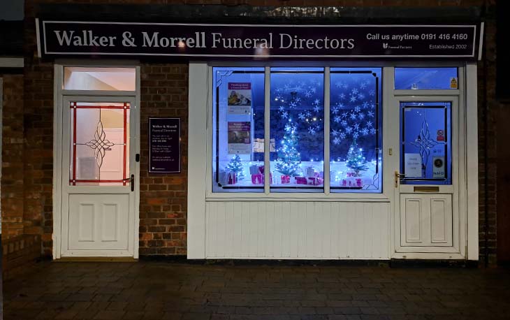 Front of Walker & Morrall window with blue fairy lights and snowflakes on the stickers.